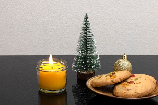 Decoração de mesa de Natal com vela perfumada e um prato de biscoitos de casca de laranja