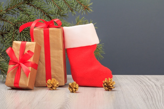 Decoração de Natal. Caixas de presente, bota de Papai Noel e galho de árvore do abeto em fundo cinza. Conceito de cartão de Natal.