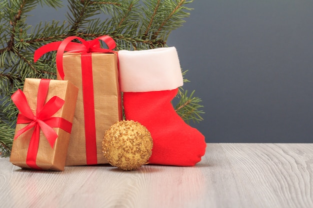 Decoração de Natal. Caixas de presente, bota do Papai Noel, bola de brinquedo e galho de árvore do abeto natural em fundo cinza. Conceito de cartão de Natal.