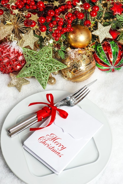 Decoração de Natal. Cenário de mesa com enfeites brilhantes, guirlandas douradas e frutas vermelhas