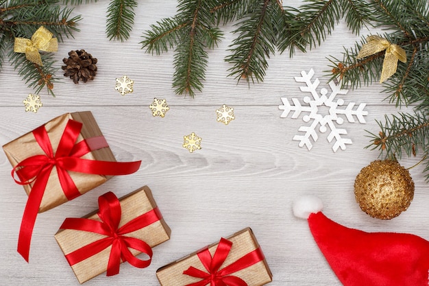 Decoração de Natal. Chapéu de Papai Noel, caixas de presente, galhos de árvore do abeto com cones e brinquedos de Natal em placas cinza. Vista do topo. Conceito de cartão de Natal.