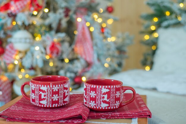 Decoração de natal com bebidas quentes em copos perto da árvore de natal