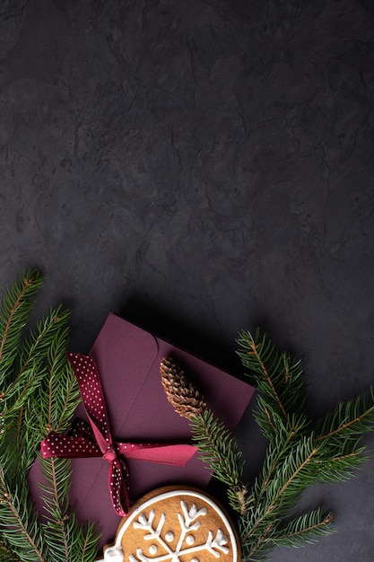 Decoração de Natal com cones de ramos de abeto e pães de gengibre em um fundo escuro vertical