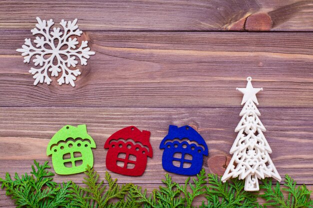 Decoração de Natal com galhos de thuja, flocos de neve, casas e abeto na mesa de madeira.