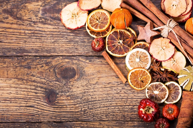 Decoração de natal com vários paus de canela de frutas secas e estrelas de anis em fundo de madeira