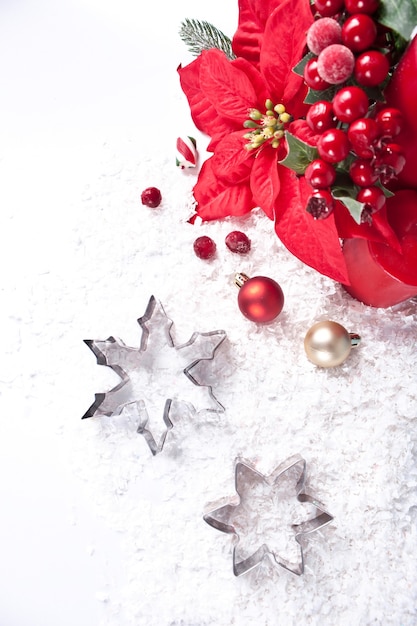 Decoração de natal com velas vermelhas, bagas, flor de poinsétia e cortadores de biscoito em forma de floco de neve. conceito de férias de natal e ano novo.