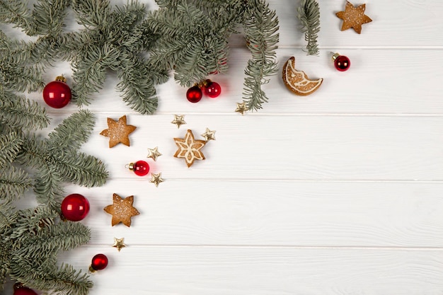 Decoração de natal de ramos de abeto e biscoitos em um fundo branco de madeira.