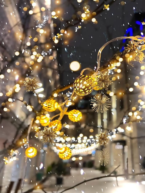 Decoração de Natal em confete de ouro de rua à noite, guirlanda de flocos de neve e luz desfocada