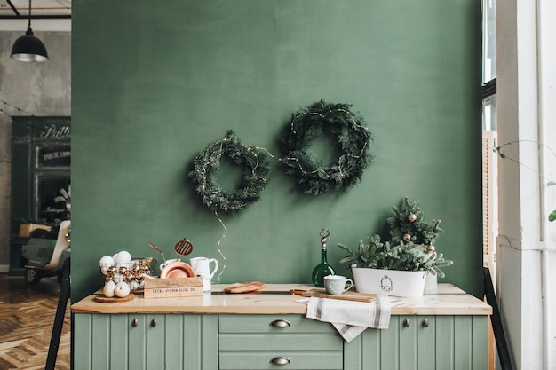 Decoração de natal festiva na cozinha com coroa de flores feita à mão feita de ramos de pinheiro e brinquedos de ouro e branco