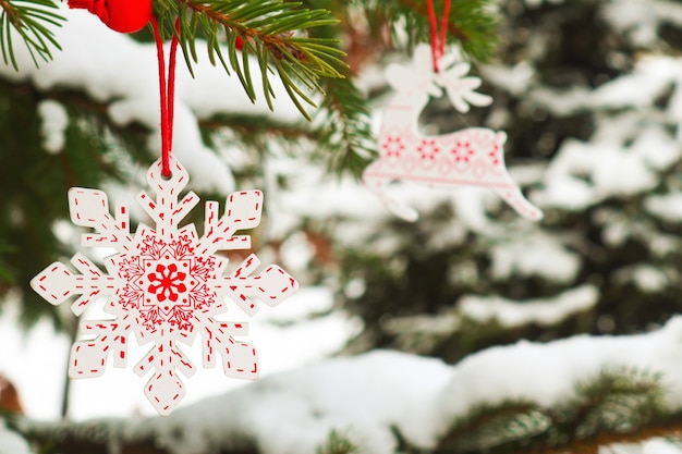 Decoração de Natal: floco de neve e veado em um galho de abeto coberto de neve