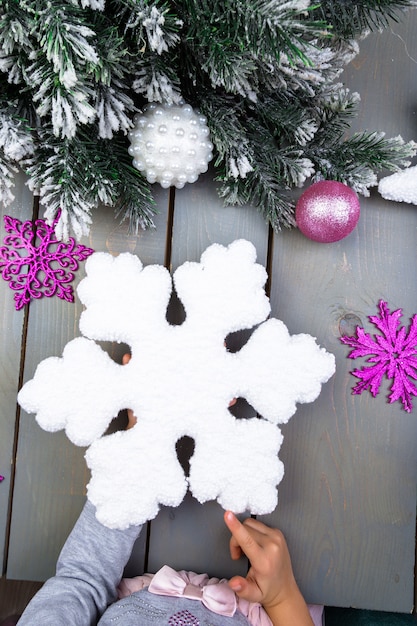 Decoração de Natal. Mão de criança com floco de neve decorativo. Vista do topo.