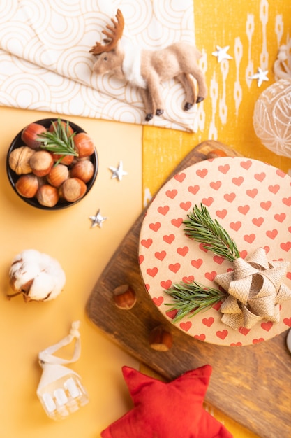 Decoração de Natal na mesa. Flatlay com caixa de presente artesanal, poinsétia, nozes, enfeites de natal