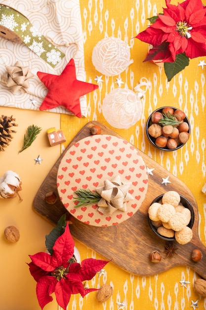 Decoração de Natal na mesa. Flatlay com caixa de presente artesanal, poinsétia, nozes, enfeites de natal