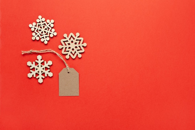 Decoração de Natal, três pequenos flocos de neve de madeira e etiqueta em vermelho brilhante