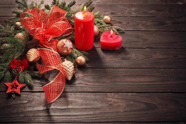 Decoração de natal vermelha e dourada com vela acesa em fundo de madeira