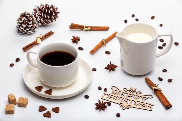 Decoração de natal. xícara de café expresso com leite, cone de árvores de natal e texto de madeira feliz natal