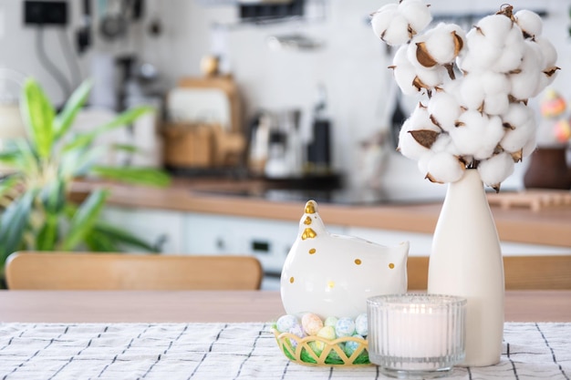 Decoração de Páscoa de ovos coloridos em uma cesta e uma galinha na mesa da cozinha em estilo rústico Interior festivo de uma casa de campo