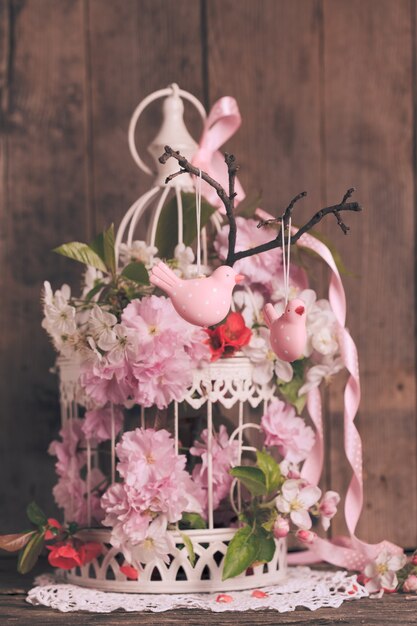 Decoração de primavera - pássaros rosa no galho em uma gaiola chique com flores