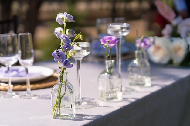 Decoração decorativa da mesa festiva. Vasos de vidro e flores frescas. Decoração de férias ao ar livre