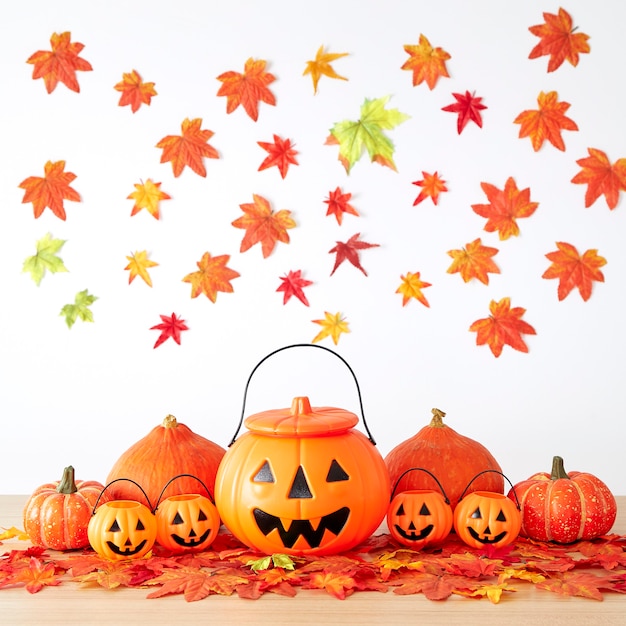 Decoração do feriado de Halloween com lanterna de jack de cabeça de abóbora e folhas de outono na mesa de madeira com fundo de parede de folhas brancas, conceito de fundo de halloween, espaço de cópia.