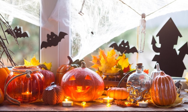 Decoração festiva da casa no parapeito da janela para abóboras de Halloween Jack o lanternas caveiras morcegos teias de aranhas velas e uma guirlanda um clima aconchegante e terrível