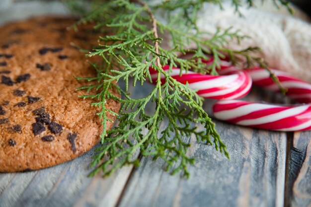 Decoração festiva de ano novo. biscoitos de chocolate de cana-de-doces e galho de zimbro em fundo de madeira rústico.