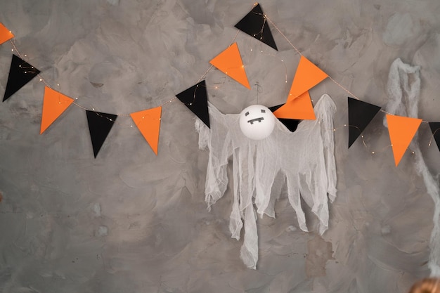Decoração festiva de Halloween bandeiras pretas laranja e fantasma pendurado na parede de concreto do interior da sala lugar para texto