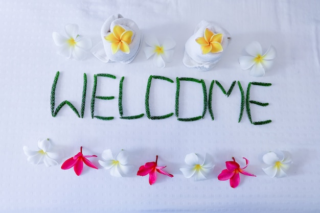 Decoração floral, toalha Floral e palavra Bem-vindo na cama no quarto de hotel