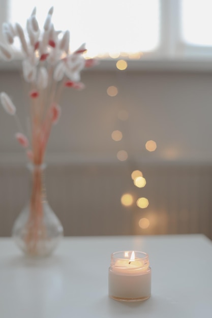 Decoração interior de casa aconchegante vela acesa na mesa contra luzes desfocadas Vela de cera de soja perfumada artesanal em um espaço de vidro para texto