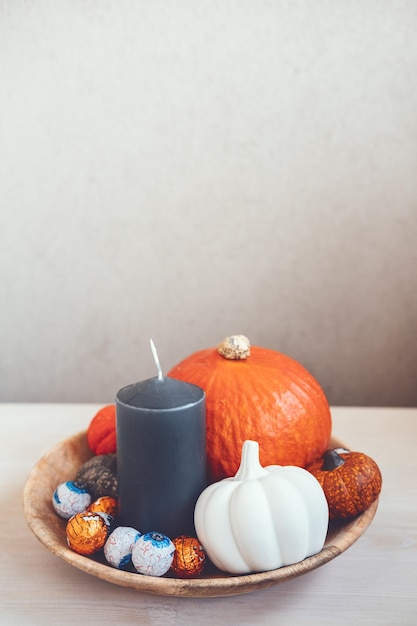 Decoração mínima do feriado de halloween com abóboras doces velas pretas em mesa de madeira dentro de casa