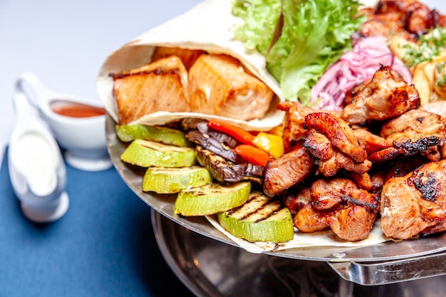 Decoração mista de carne grelhada, vegetais fritos e filés de salmão grelhado em prato quente