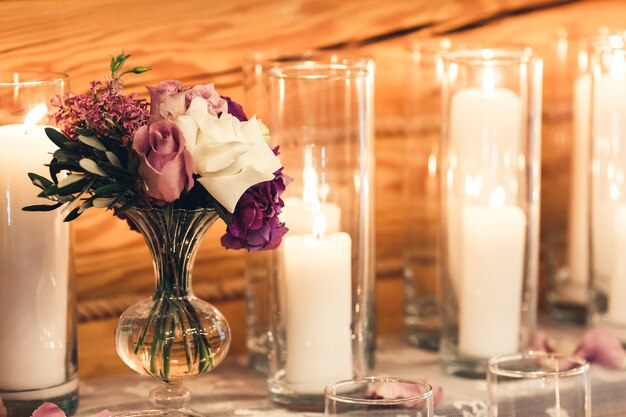 Decoração na mesa, velas em copos, flores roxas em vasos