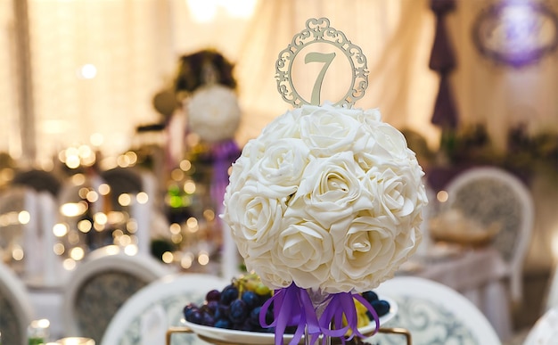Decoração no casamento em cores brancas e roxas um buquê de uma bola com um número de mesa