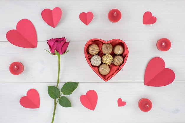 Decoração romântica do dia de Valentim com rosas e chocolate em uma tabela de madeira branca.