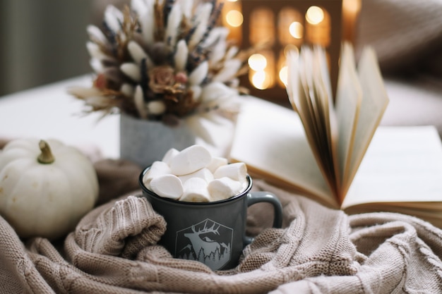 Decoração sazonal de outono com xícara de café, flores secas, abóbora branca e um livro