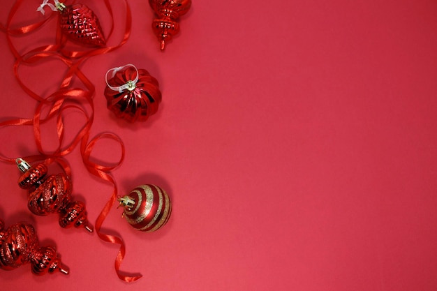 Decoración de adornos navideños rojos sobre fondo rojo con espacio de copia. Tarjeta de felicitación de año nuevo. Estilo minimalista. Endecha plana.