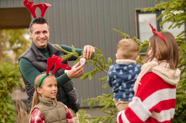 Decoración del árbol de año nuevo. Una familia decorando un árbol de año nuevo juntos y luciendo felices.