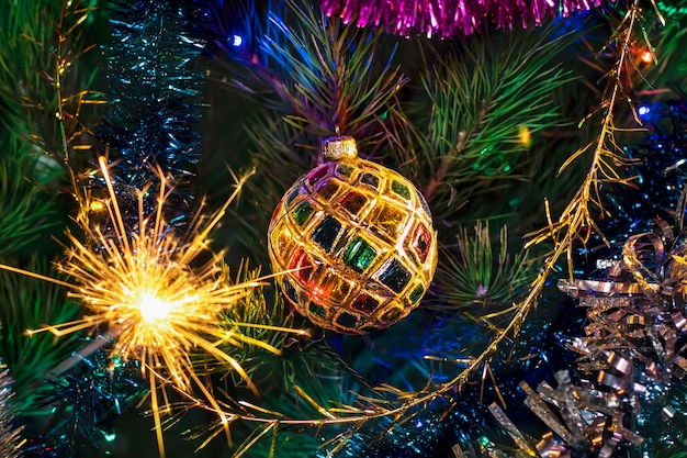 Decoración del árbol de Navidad con una bola brillante y fuegos artificiales con chispas ardientes