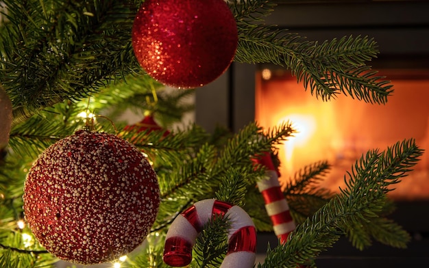 La decoración del árbol de Navidad y las luces de adorno rojo cierran el fondo de la chimenea ardiente