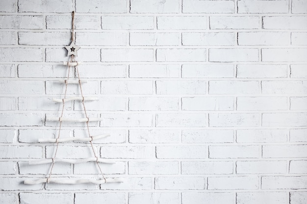 Decoración de árbol de Navidad de madera sobre fondo de pared de ladrillo blanco con espacio de copia