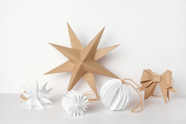 Decoración de bolas y estrellas de papel de Navidad Decoración nórdica de Navidad hecha a mano sobre un fondo claro contra la pared Diseño de estilo bohemio escandinavo Adorno mínimo de bricolaje Origami estructural Cero desperdicio