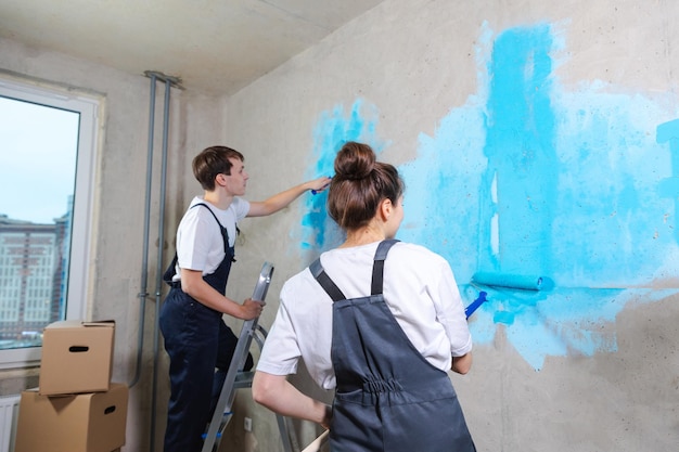 Decoración de la casa concepto de renovación diy pareja feliz en la habitación vacía de la casa nueva pintura de pared