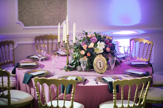 Decoración de la cena festiva con flores rosas en la mesa nupcial en el interior del restaurante. Mesa decorada para celebración.