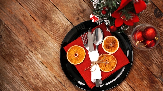 Decoración de la cena de Navidad con naranjas secas y una servilleta roja sobre una placa negra