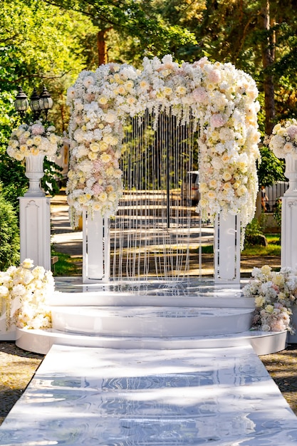 Decoración de ceremonia de boda. Arco blanco con flores. Fondo del parque verde. Fiesta de verano.