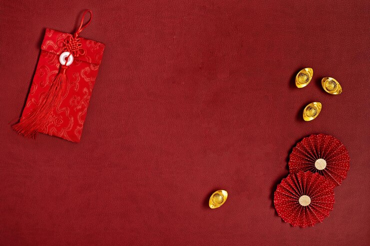 Decoración china de año nuevo con lingotes de oro, abanicos de papel rojo y sobre con nudo de símbolo de buena suerte.