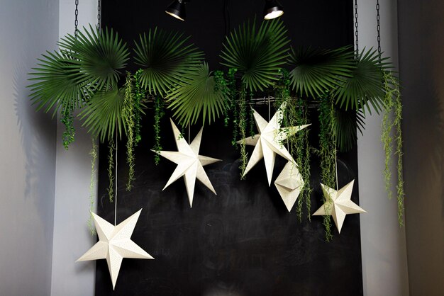 Decoración colgante en la pared negra en forma de estrellas y hojas de palma.