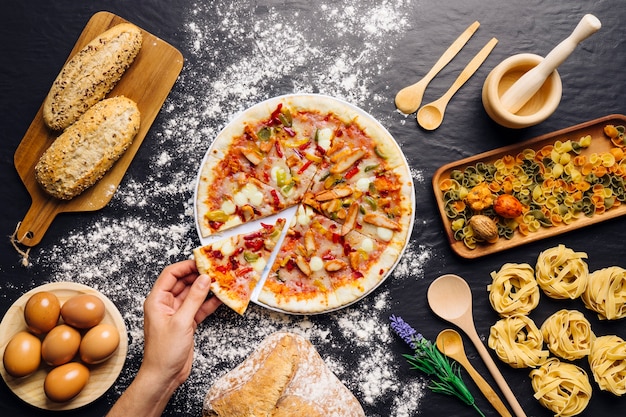 Foto decoración de comida italiana con mano cogiendo trozo de pizza