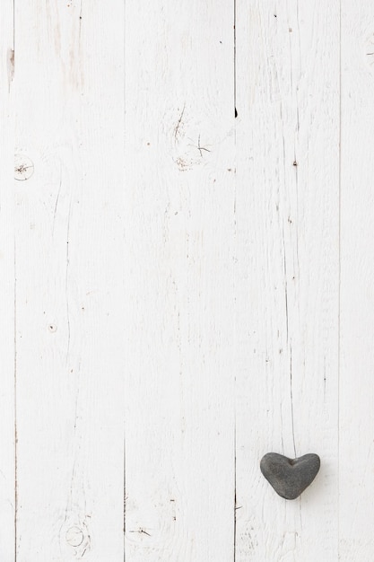 Decoración de corazón de piedra sobre una mesa de madera envejecida Fondo para postales con espacio para texto Temporada festiva Corazón de piedra natural en la esquina del marco