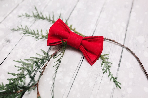 Decoración de la corbata de lazo de la Navidad con nieve en el fondo de madera blanco.